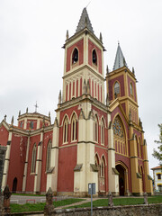 Fototapeta na wymiar Vistas de la fachada roja y ocre de estilo neogótico de la Iglesia de San Pedro Advíncula, en Cobreces, Cantabria, verano de 2020