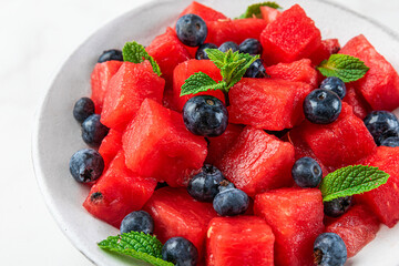 Fresh summer watermelon and blueberry salad with mint in a plate on white background. close up
