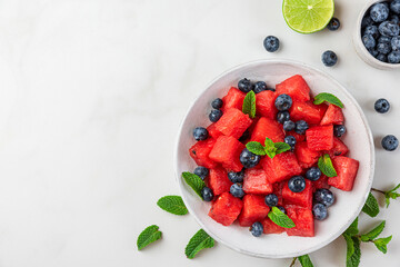 Watermelon and blueberry fruit salad with mint and lime juice in a plate on white background. Top...
