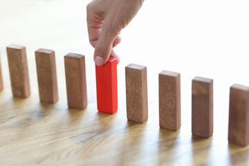 Man hand choosing red block among wooden closeup