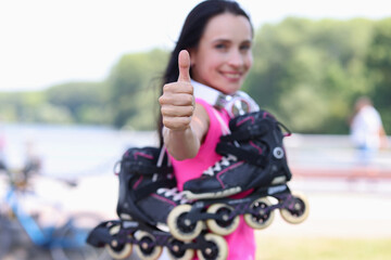 Smiling woman with rollers on shoulder showing thumb up closeup