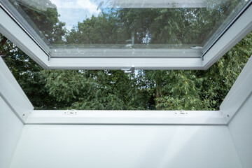 Selective focus view at slightly opened white Tilt Window Skylights  at attic and defocused of...