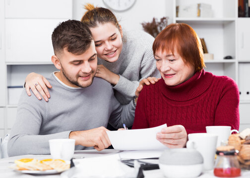 Happy Young Man With Wife And Mother Getting Good News, Reading Mail Together In Home Interior