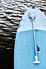 Paddleboard and surf board with paddle on wavy water surface background close up. Surfing and SUP...