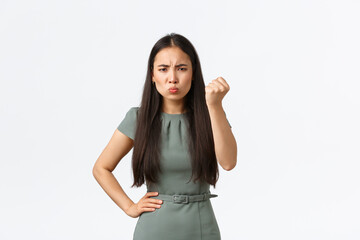 Fototapeta na wymiar Small business owners, startup and work from home concept. Angry and disappointed asian businesswoman scolding employee, looking mad and pouting, shaking fist threatening, white background