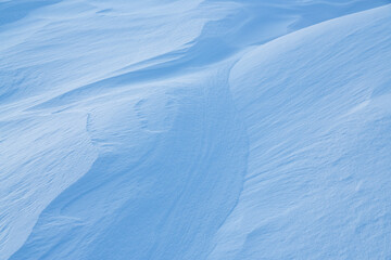 Beautiful winter background with snowy ground. Natural snow texture. Wind sculpted patterns on snow surface.