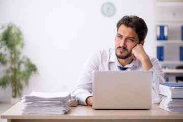 Young male employee unhappy with excessive work in the office