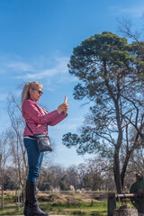 Side view of an adult woman taking a picture in a park