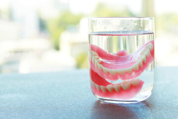 False teeth swim in transparent water glass