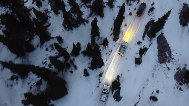 Aerial footage of 4X4 vehicles traveling through the rocky mountains, camera pans up to show the sunset