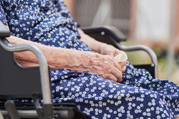 Detail of hands of a 90 year old woman on wheelchair holding a tissue
