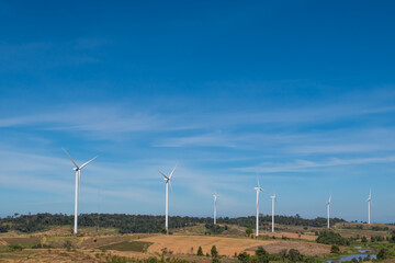 Wind turbines generating electricity over blue sky background. Windmill on autumn mountain landscape.