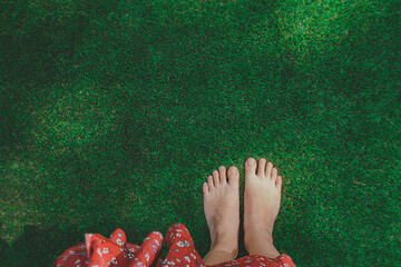 women bare feet on flat green grass lawn, top view. woman dressed in red dress. meditation in nature. selective focus