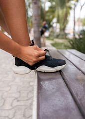 hispanic woman's hand tying shoelaces of sneakers - sport concept