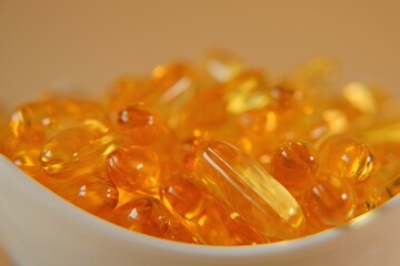 Fish oil capsules in a white ceramic bowl. omega fatty acids.Natural supplements and vitamins. High...