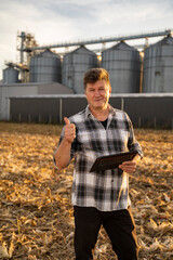 Man engineer  with tablet showing thumbs up outside the agricultural silo 