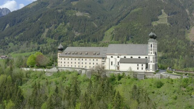 Aerial view panning left shot, Scenic view of Strechau castle in Austria, bright blue sky and mountains in the background.