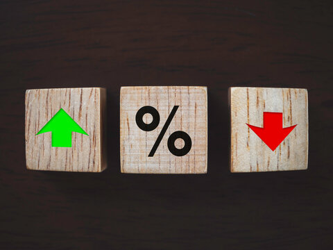 Business, Interest rate financial and mortgage rates concept. Close up percentage symbol with red decrease and green increase arrow icon symbolizing on wooden cube block on dark wooden background.