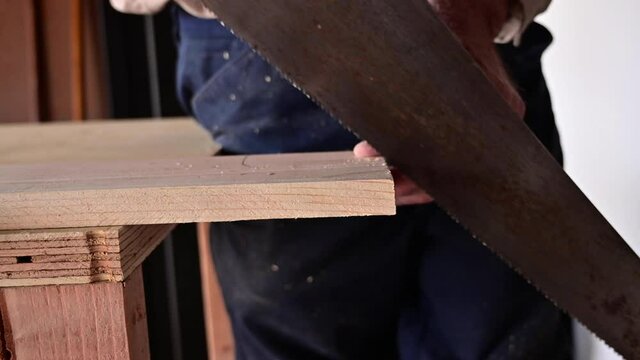 Woodworker Uses Handsaw To Cut Plank Of Wood At The Workshop. close up