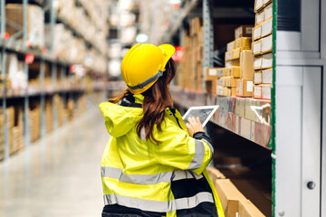 Portrait of smiling asian engineer in helmet woman use tablet computer order details and checking goods and supplies on shelves with goods background in warehouse.logistic and business export