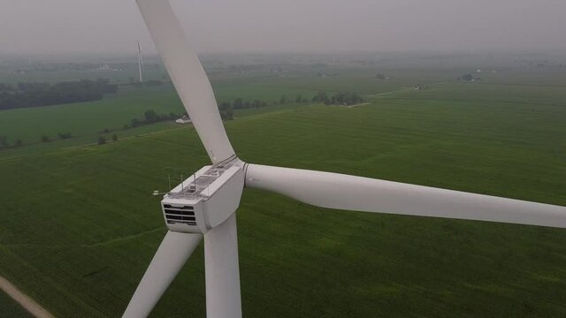 Close Up Of Rotor Blade, Nacelle, And Hub Of A Wind Turbine At DTE Wind Farm In Gratiot County, Ithaca, Michigan Overlooking Lush Field In Background. aerial