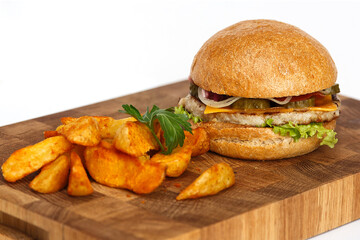 Juicy burger and fried potatoes on a wooden cutting board