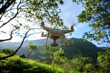 White drone with camera flying in summer mountains