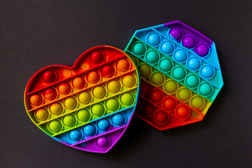 Pop it fidget toys on black background. Rainbow heart and octagon anti stress fidget. Fine motor...