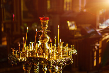 a splendor floor church candle holder with burning candles shot close-up on a dark background. Selective focus, blurry background, dim lighting.