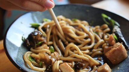 Woman eating delicious udon in an Asian cuisine restaurant. Woman eating noodles with vegetables...