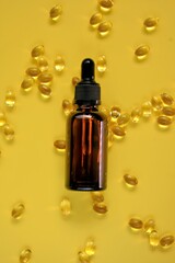 Vitamin D. Oil extract and gelatin capsules with vitamin D on a bright yellow background.Vitamins and minerals. Food supplements. 