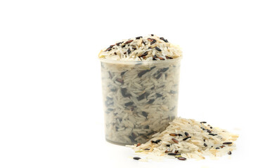 Three kinds of rice in a plastic rice measuring cup, small heap rice is besides, the image on white background, front view, close up image of mixed rice, white, brown, black.