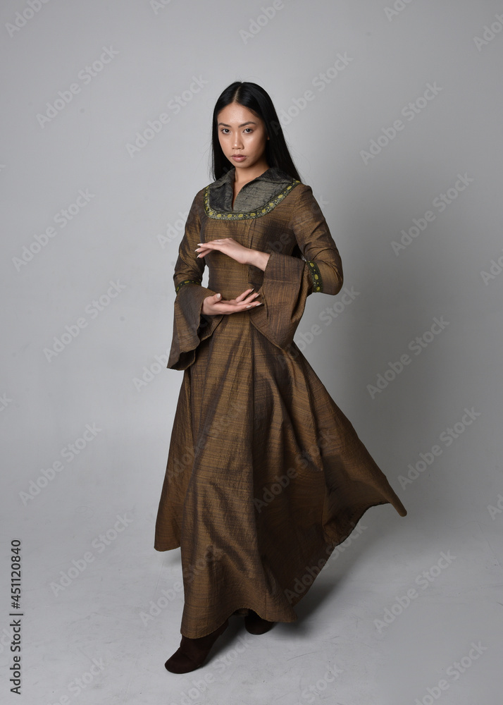 Wall mural Full length  portrait of beautiful young asian woman with long hair wearing medieval fantasy gown costume. Graceful standing posing  isolated on studio background.