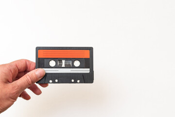 Hand holding old magnetic audio cassette on white background, close-up, copy space