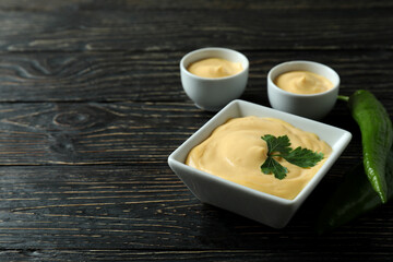 Bowls with cheese sauce and pepper on wooden table