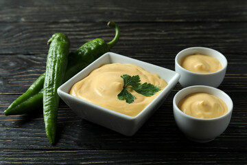 Bowls with cheese sauce and pepper on wooden table