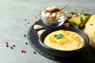 Tray with cheese sauce and ingredients on gray textured table