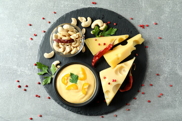 Tray with cheese sauce and ingredients on gray textured table