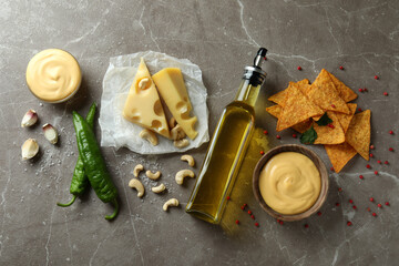 Bowls with cheese sauce and ingredients on gray textured table