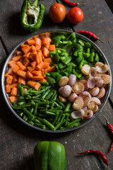Chopped raw food ingredients carrots, onions, beans and capsicum on a plate. Top view. 