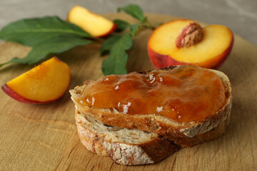 Sandwich with peach jam and peach fruits on round wooden board