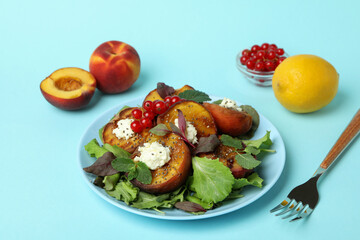 Plate of salad with grilled peach on blue background