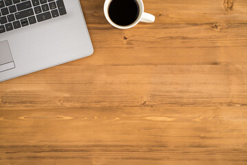 Top view photo of laptop and cup of coffee on isolated wooden table background with copyspace