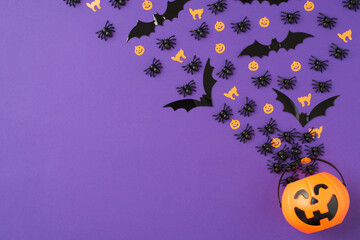 Top view photo of halloween decorations orange cats pumpkins silhouettes spiders and bats crawling and flying out of the pumpkin basket on isolated violet background with copyspace