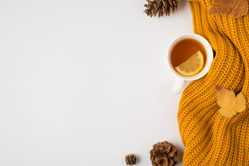 Top view photo of yellow knitted sweater cup of tea with lemon yellow autumn leaves and pine cones...