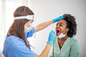 Close up of female health Professional in PPE introducing a nasal swab to a senior female patient...