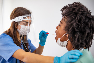 Doctor in protective workwear taking nose swab test from young woman. Experienced lab technician...