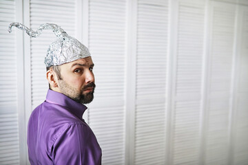 Bearded funny man in a cap of aluminum foil. Concept art phobias.Conspiracy theory. Conspiracy....