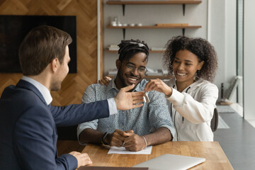 Young African couple getting keys to first own house from realtor finish formal meeting in agency...