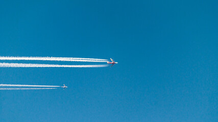 A pair of planes flying next to each other. A huge passenger airliner and a small plane. Traces of...